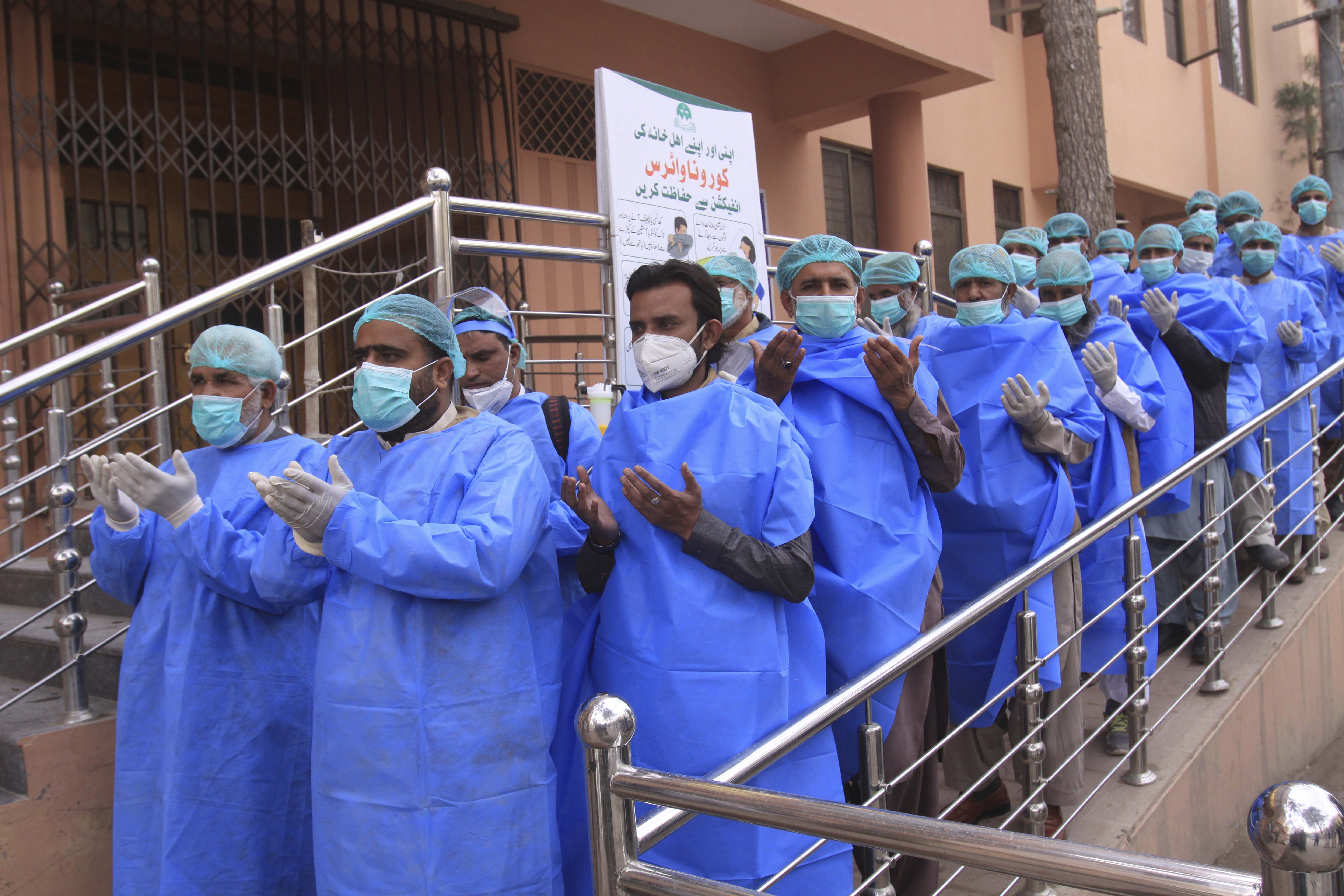 Hospital staff pray before joining their shift, outside a hospital setup for coronavirus infected patients in Quetta, Pakistan
